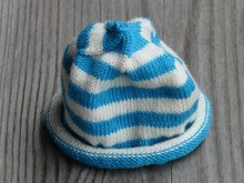 A blue and white striped bknitted baby hat representing charitable crafting items