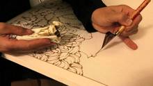 A man using a special pen called tjanting,, drawing with melted wax to make batik fabric